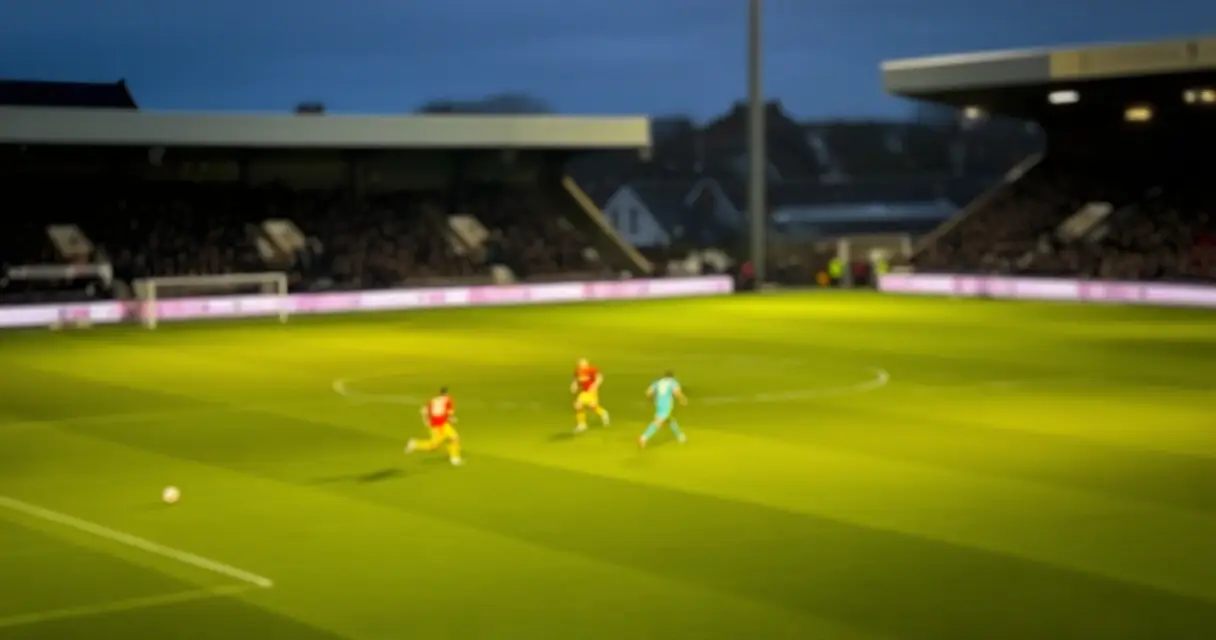 Jalkapallopelaajat maalintekotilanteessa stadionilla valaistuksen alla